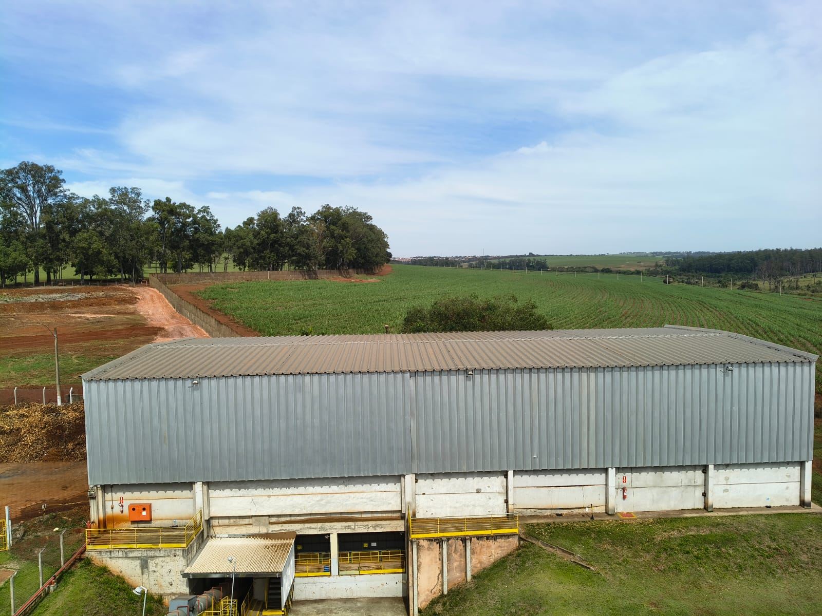 Galpão metálico rural com lavoura ao fundo, durante inspeção de SPDA