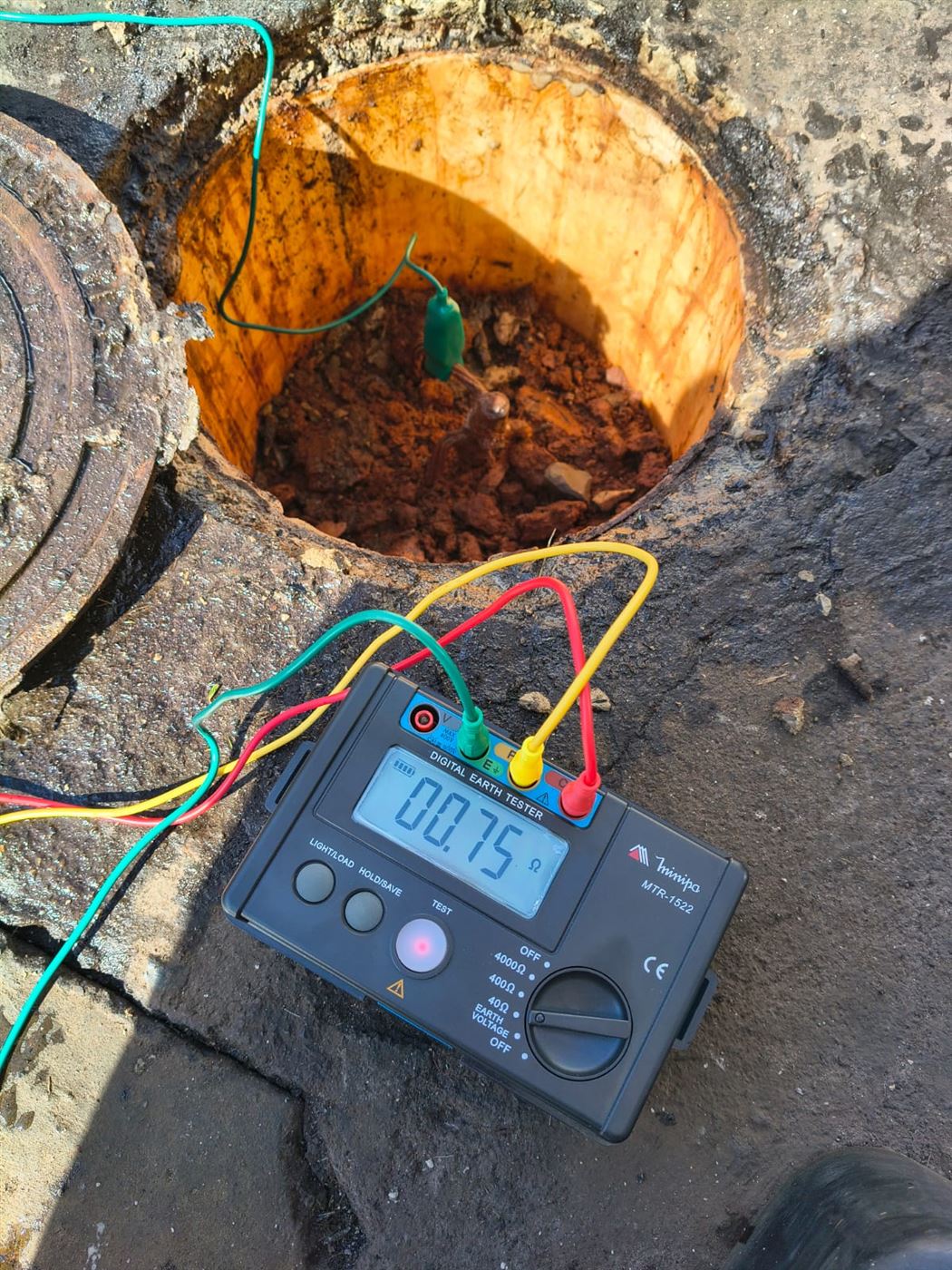 Terrômetro digital indicando 0,75 ohm em caixa de inspeção de aterramento